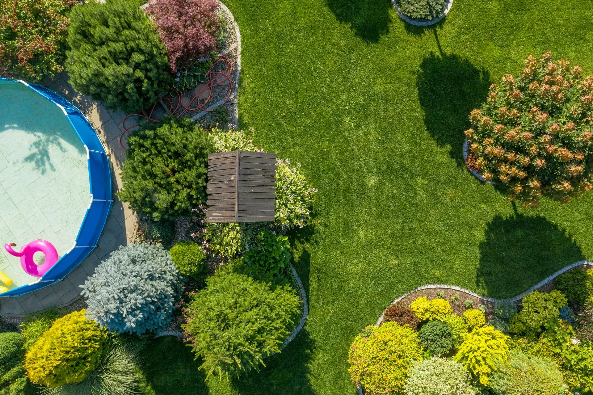 Well-maintained garden with pool, flowers, and trimmed grass.